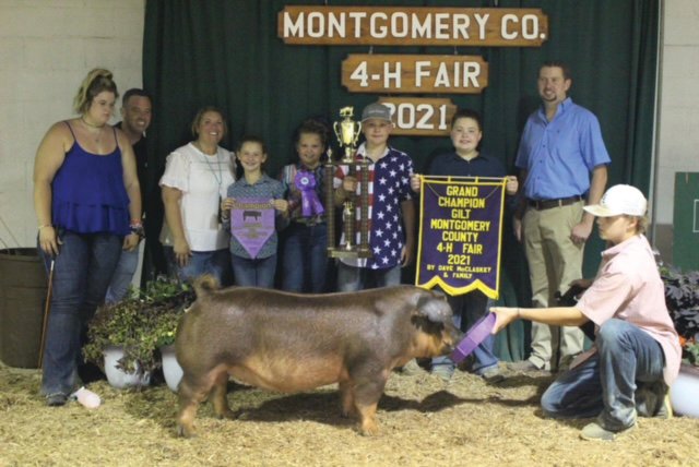 Laine Barnett, center, stands with his trophy after winning grand champion gilt at the Montgomery County 4-H Fair.