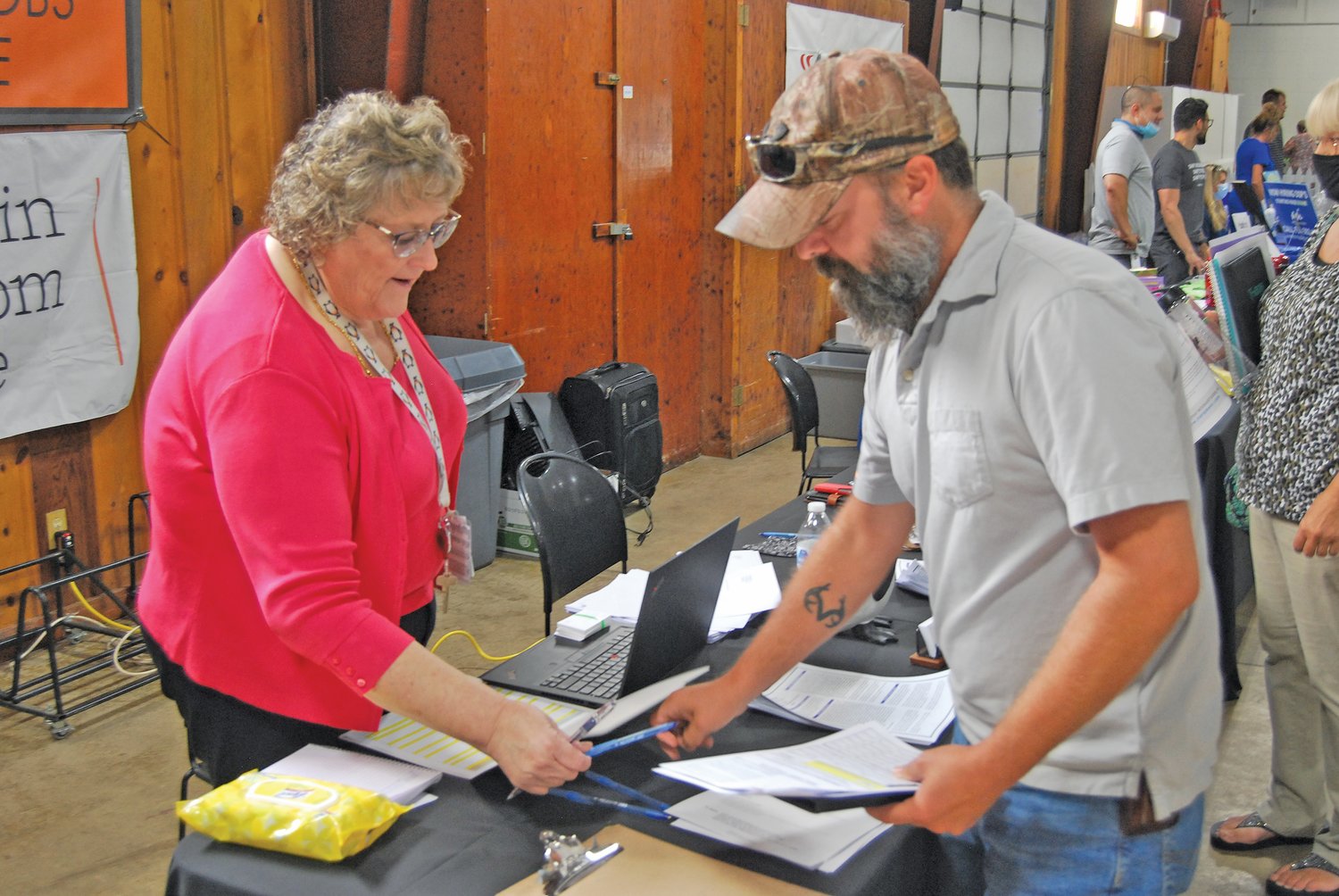 Bonnie Mann, director of human relations for Penguin Random House, hands a pen to Dan Busenbark, who gathered information on job opportunities Thursday at the Crawfordsville/Montgomery County Job Fair at the Montgomery County Fairgrounds.