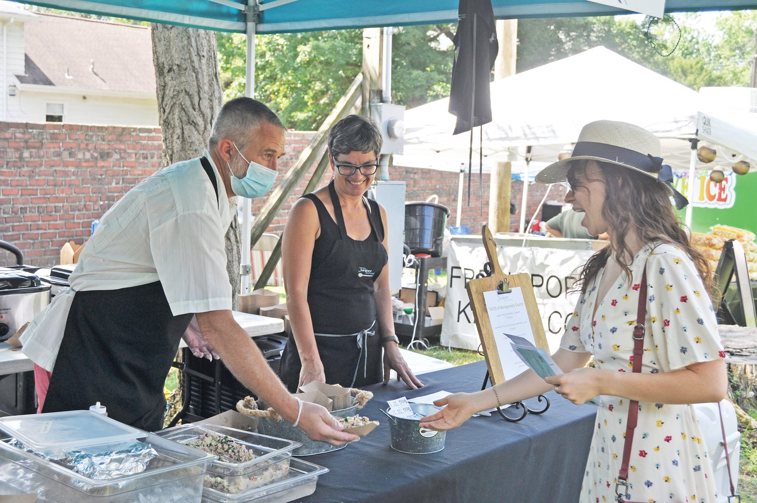 Doug Miller, left, and Lali Hess of The Juniper Spoon serve salad to a customer at the Taste of Montgomery County on the grounds of the General Lew Wallace Study & Museum on Saturday.