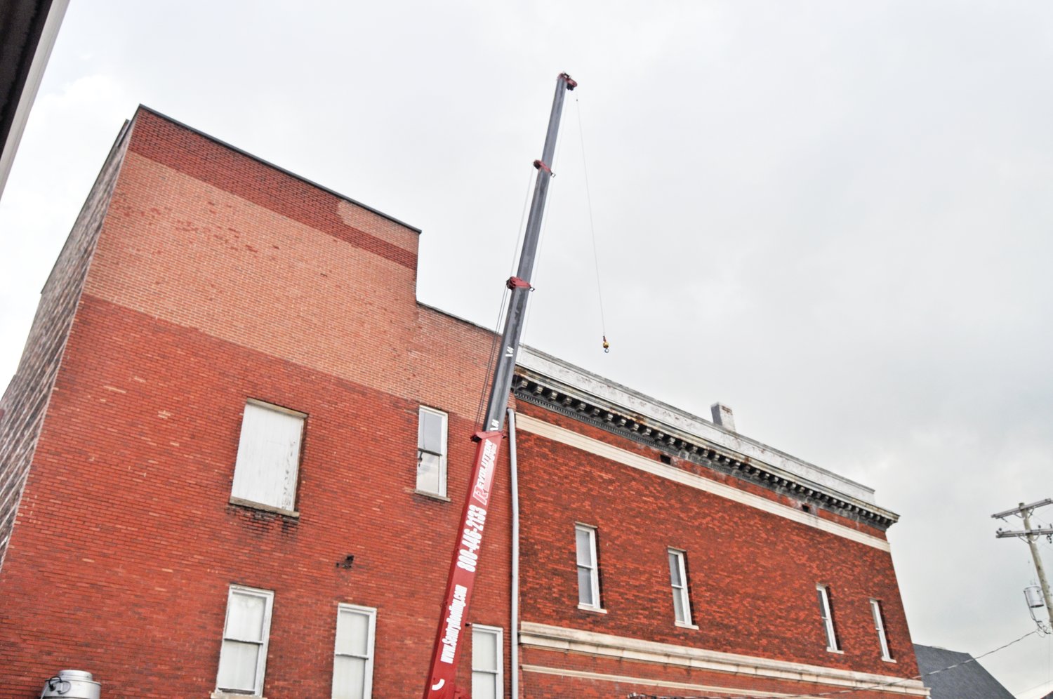 A crane reaches the top of the Masonic Cornerstone Grand Hall & Event Center on Monday. Crews from Sentry Roofing were in the process of starting long-planned work to replace the historic structure