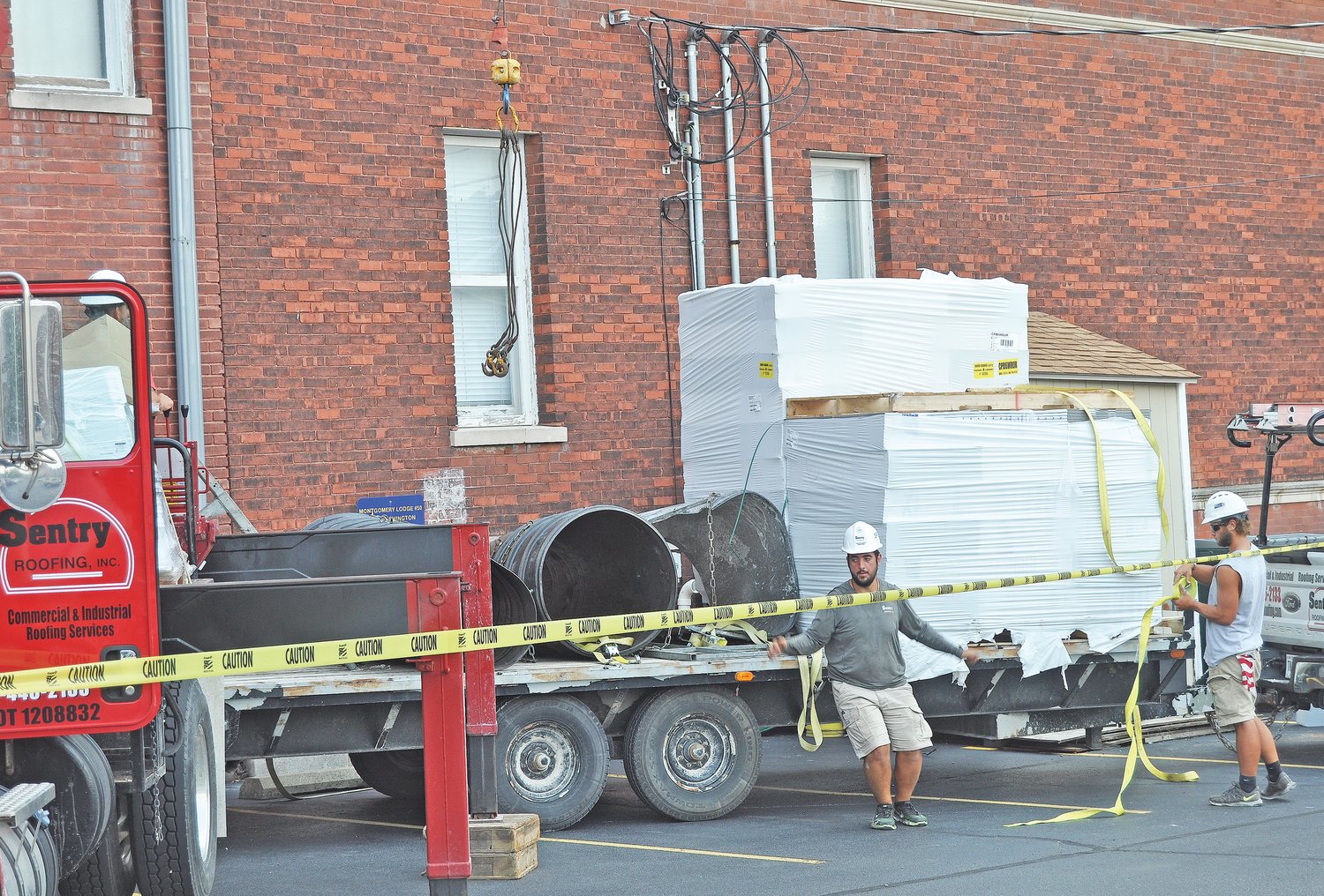 Workers from Sentry Roofing prepare to hoist supplies onto the roof of the Masonic Cornerstone Grand Hall & Event Center on Monday. The crews were beginning the process of replacing the roof of the historic downtown structure.