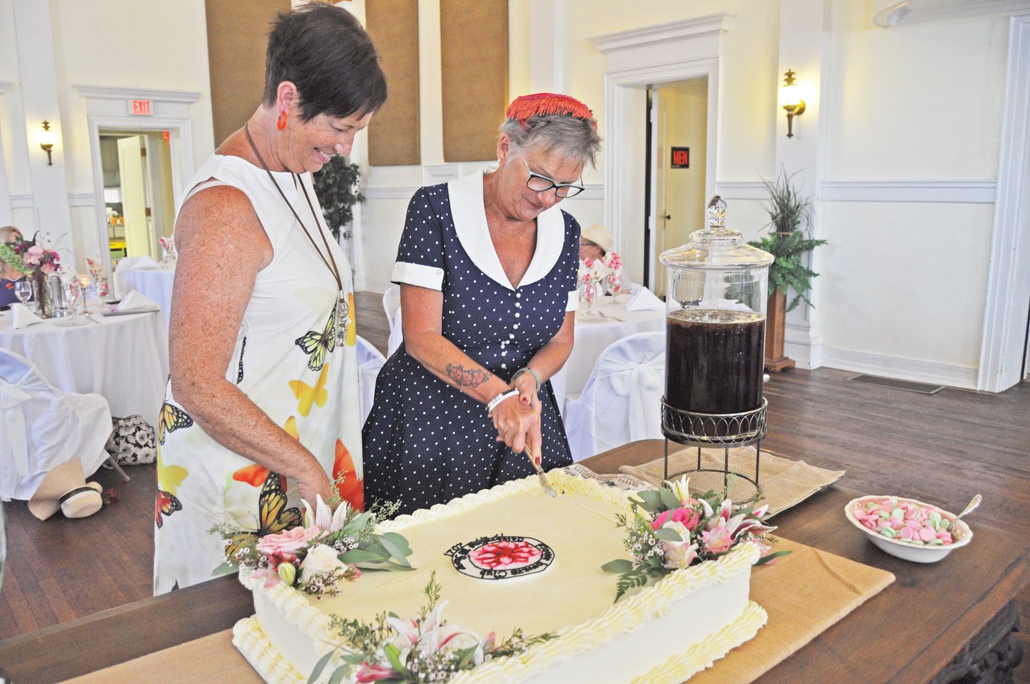 Terri Trinkle cuts the cake as Paula Furr watches during a 100th anniversary celebration for the Flower Lovers Garden Club at the Masonic Cornerstone Grand Hall and Event Center on Wednesday.