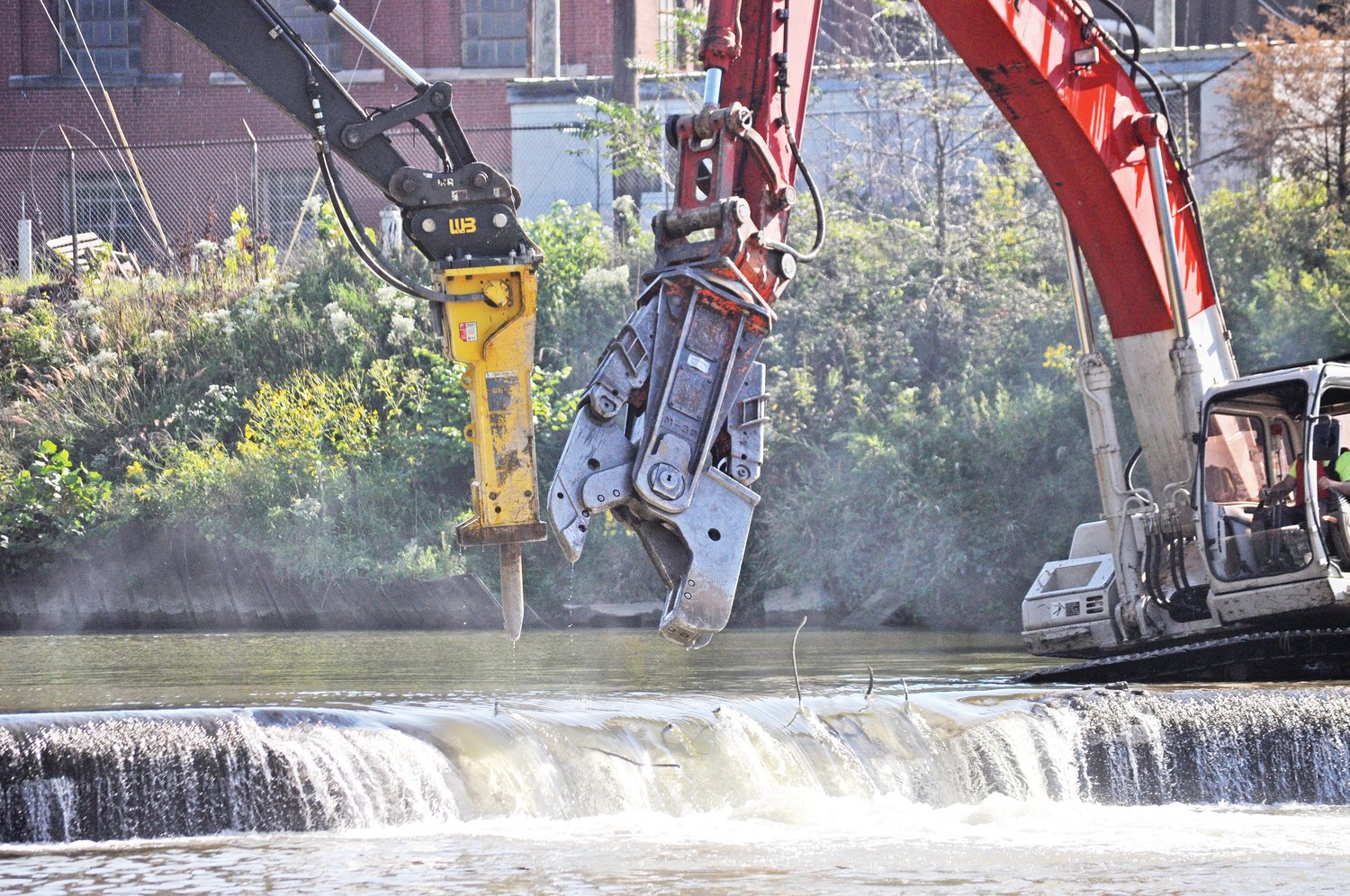 Heavy machinery demolish the Sugar Creek lowhead dam on Tuesday.
