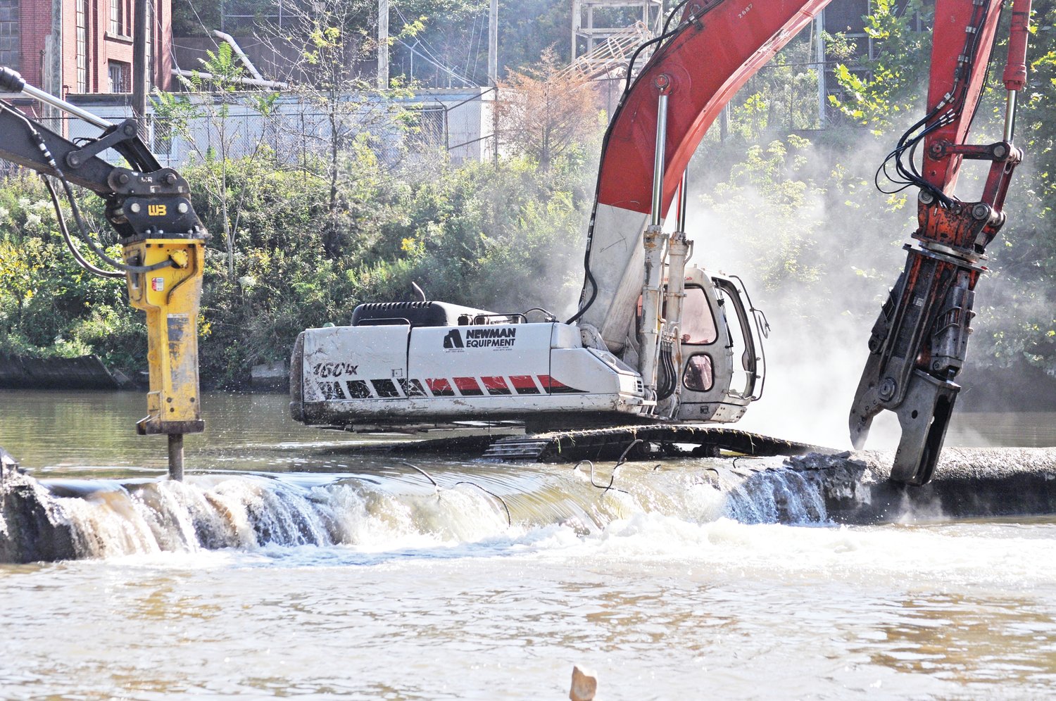 Heavy machinery cut in to the Sugar Creek lowhead dam on Tuesday.