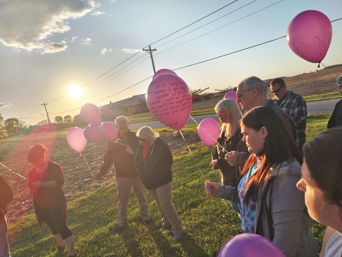 Chelsy Lawrence, second from right, holds a balloon at a celebration of life ceremony for her brother, Travis Lawrence, on the first anniversary of his death in May.