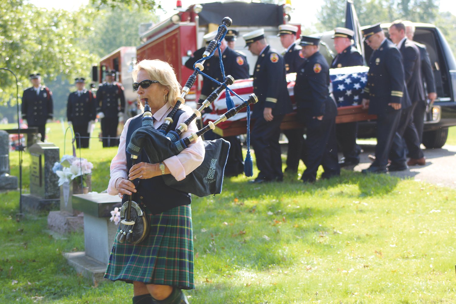 A bagpiper plays Monday as members of the Crawfordsville Fire Department carry the flag-draped casket of longtime fire chief Dennis R. Weir to the grave site at Oak Hill Cemetery North.