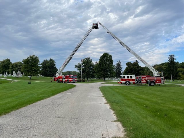 Two aerial trucks were set up at the entrance to Oak Hill Cemetery North for retired fire chief Dennis Weir.