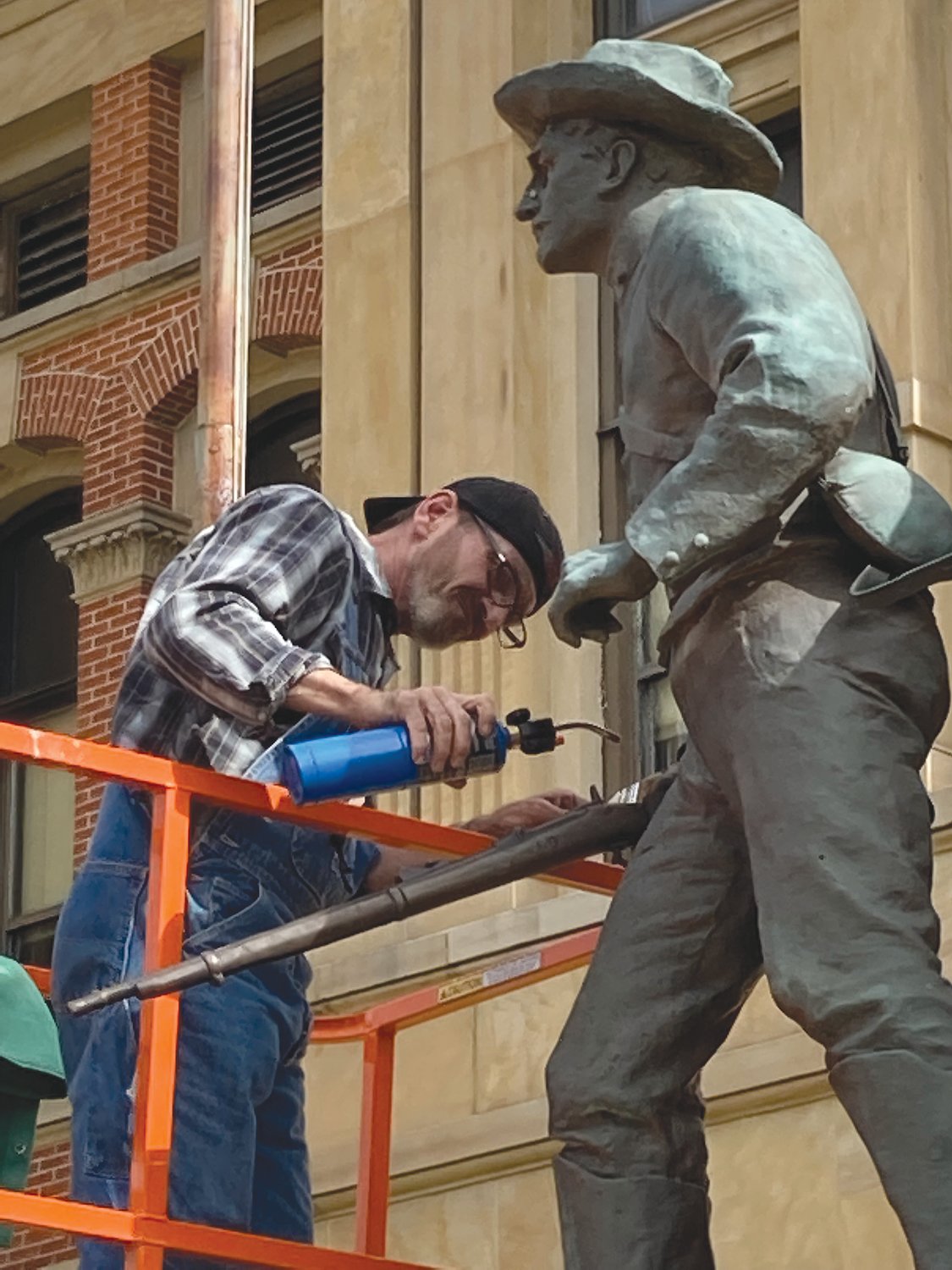 Brent Corl of Sincerus Bronze Art makes repairs Wednesday to the gun on the county's war memorial. The gun was broken decades ago.