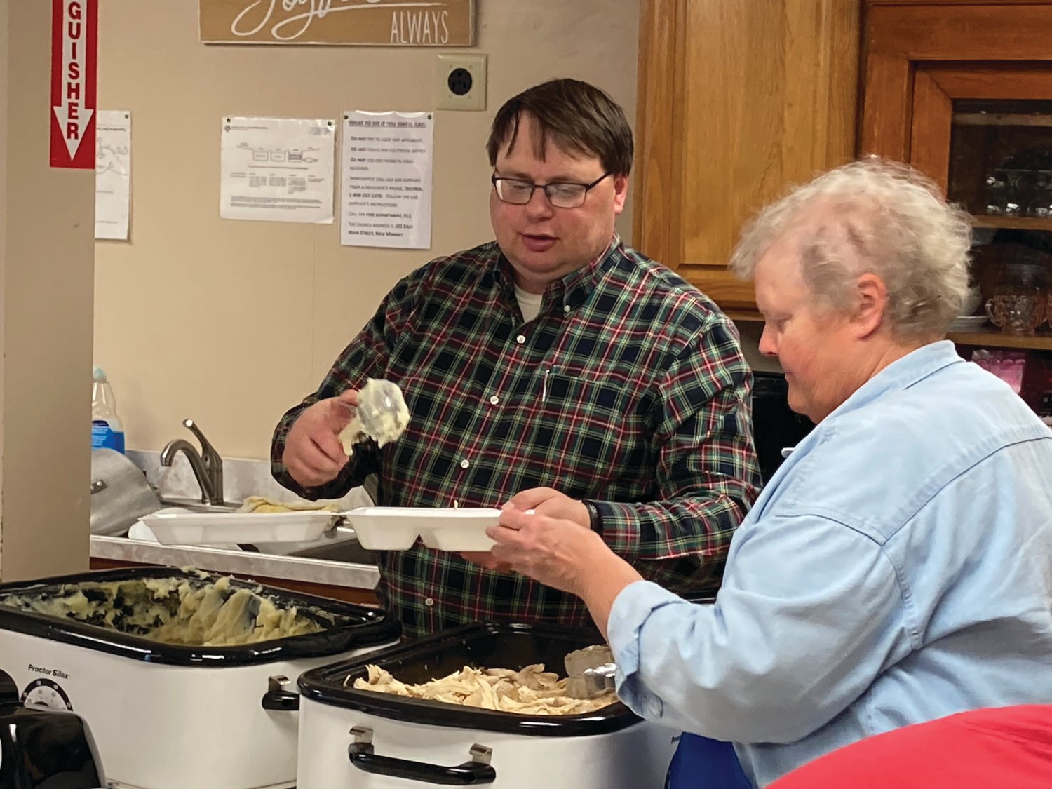 Pastor Bill Pike scoops mashed potatoes Saturday onto a tray held by Ladonna Howard at New Market United Methodist Church