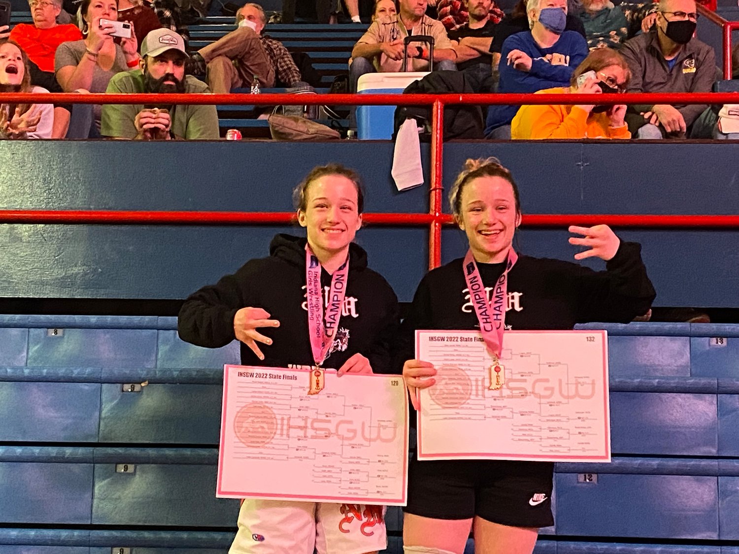 Senior twin sisters Catie (left) and Cailin (right) celebrate their state championships together on the podium at the Girls State Wrestling Finals in Kokomo. The sister duo has each won three state titles to cap off a stellar career.