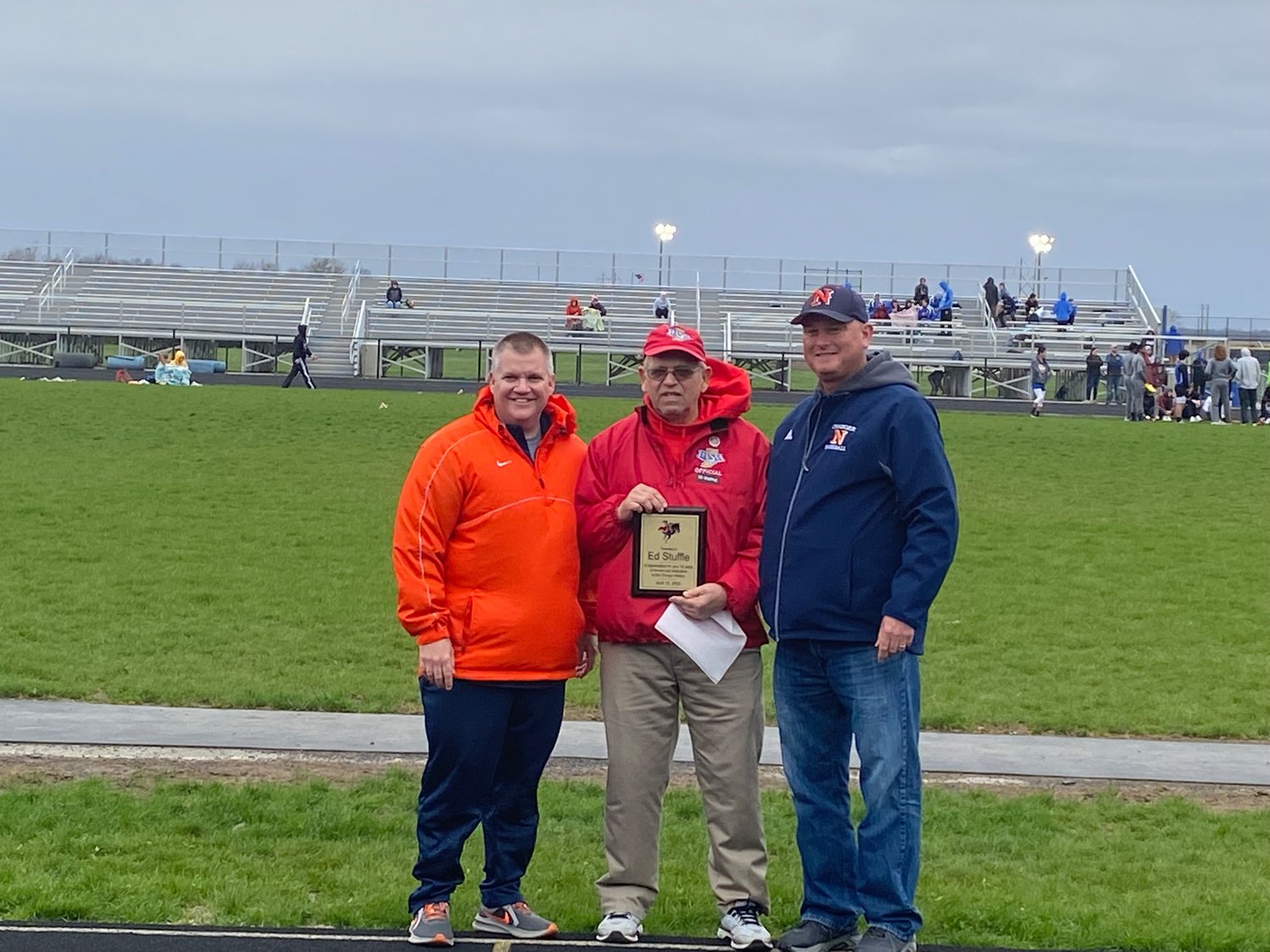 Ed Stuffle (center) is presented with an honor plaque by North Montgomery track coach Josh Thompson (left) and North Montgomery Athletic Director Matt Merica (right) for his 50 years of service and dedication to the Charger Relays.