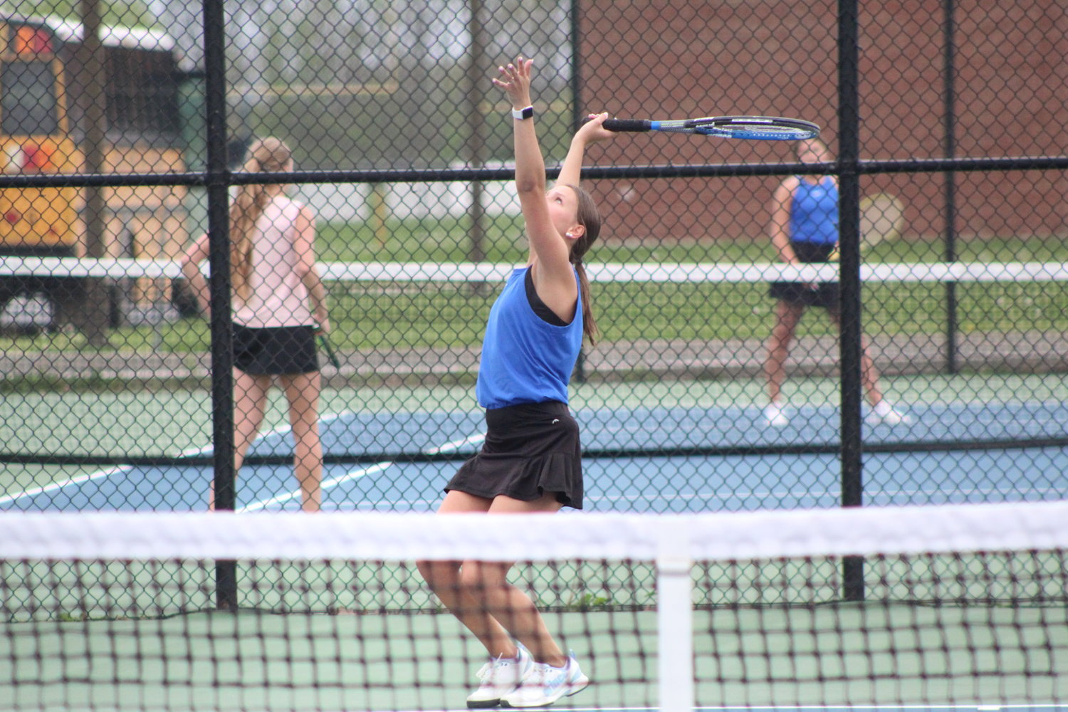 Reese Minnette goes up for a serve during her match at two singles.