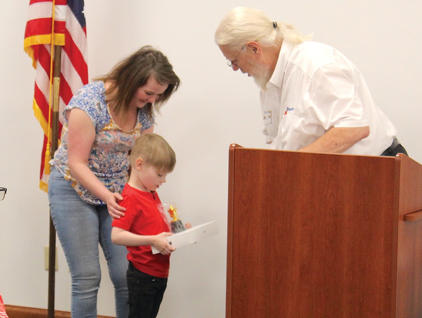 Mitchell Shell, 6, and mother Nicole Crombie receive an iPad pre-equipped with communication support for special needs children Thursday from Crawfordsville Kiwanis President Gary Behling during a special meeting at the Crawfordsville District Public Library.