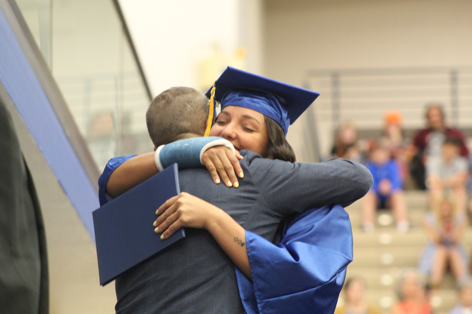 Alyx Bannon gives a hug to CHS school board member Kent Minnette as she walks across the stage to receive her diploma.