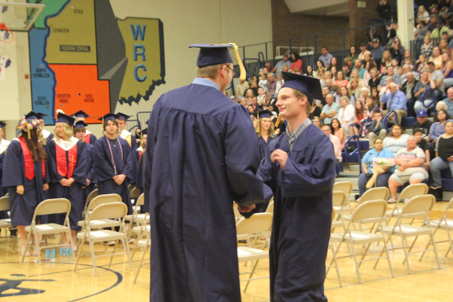 Gavin Kiger and Nathan Newell shake hands while walking into commencement.