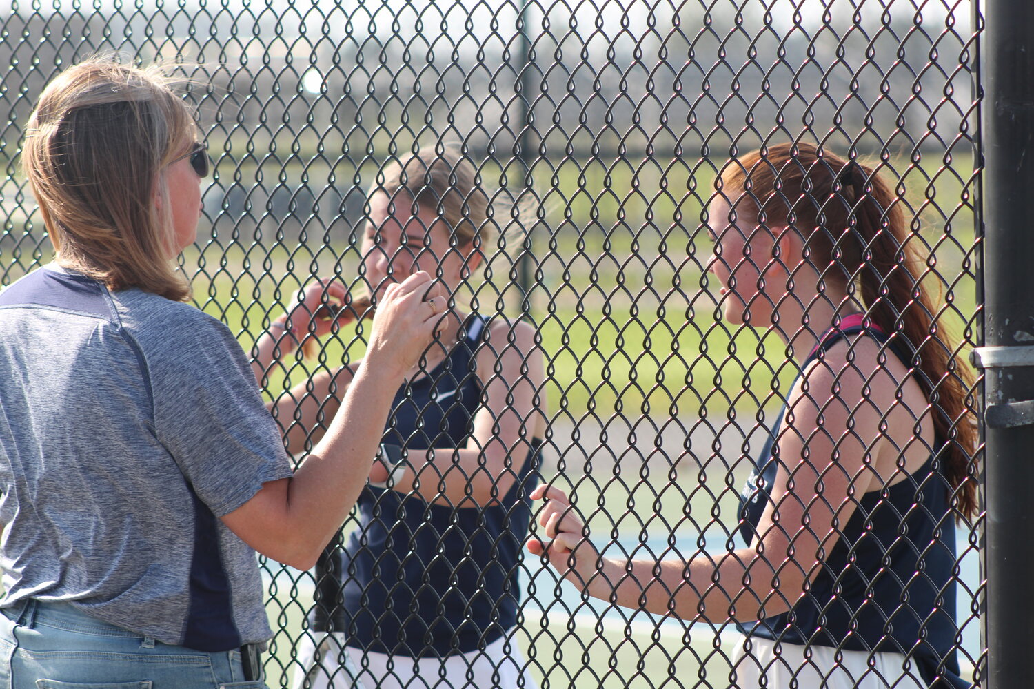 Charger coach Lori Guard speaks with her 2 doubles team during a break in the action.