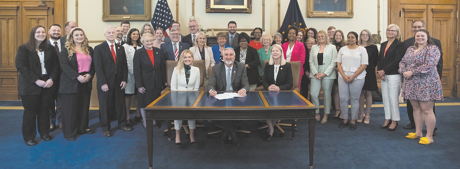 Gov. Eric Holcomb (seated, center) ceremonially signs legislation sponsored by State Rep. Sharon Negele (R-Attica) (seated, right) into law to expand Medicaid recipients' access to long-acting reversible contraception like IUDs and implants May 24.  Joining Negele for the ceremonial signing were various state, local and industry leaders.