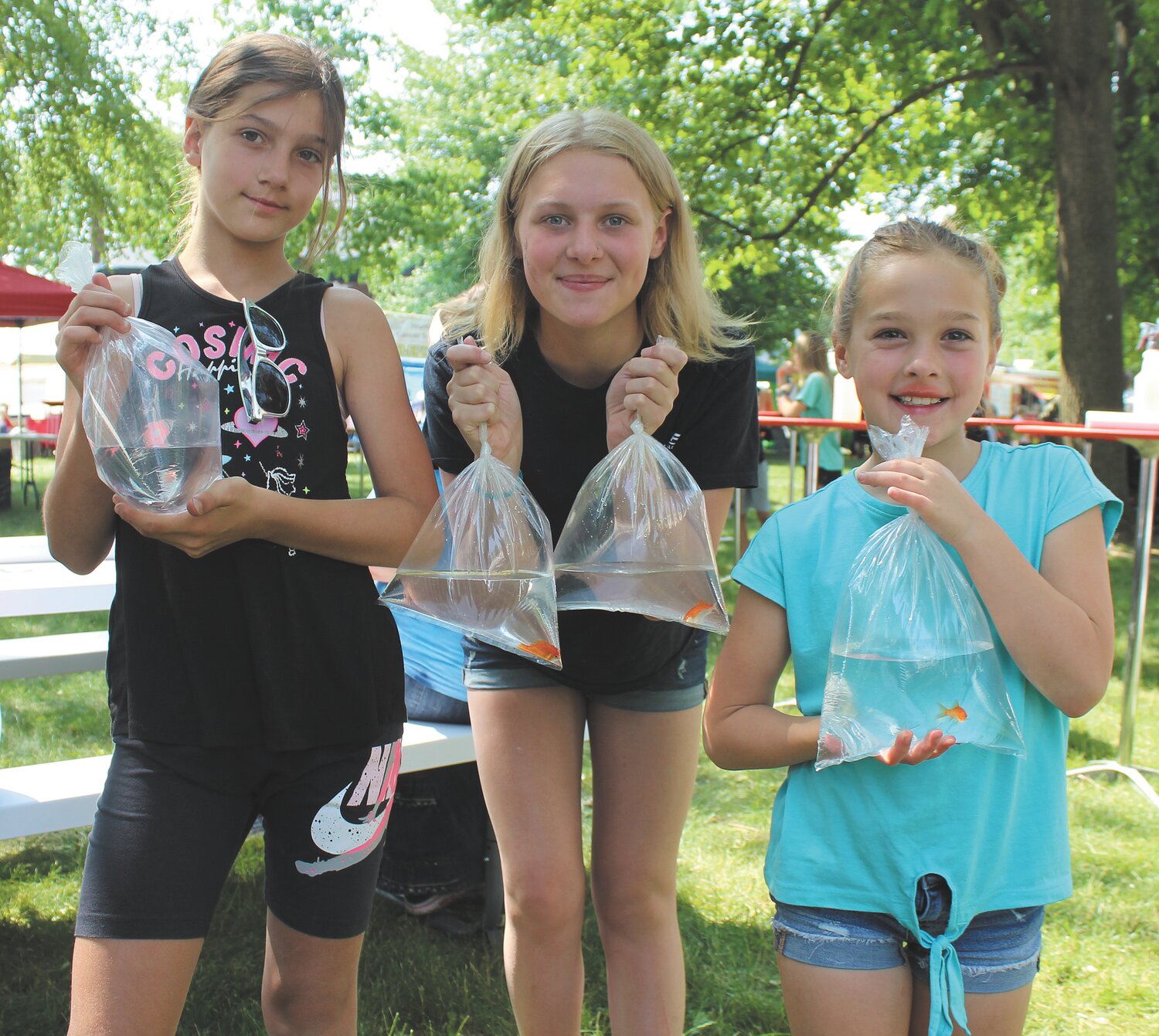 Addison Potts, 9, left, Lilyanah McCollum, 14, center, and Keagan Strawser, 8, show off the gold fish they won Friday.