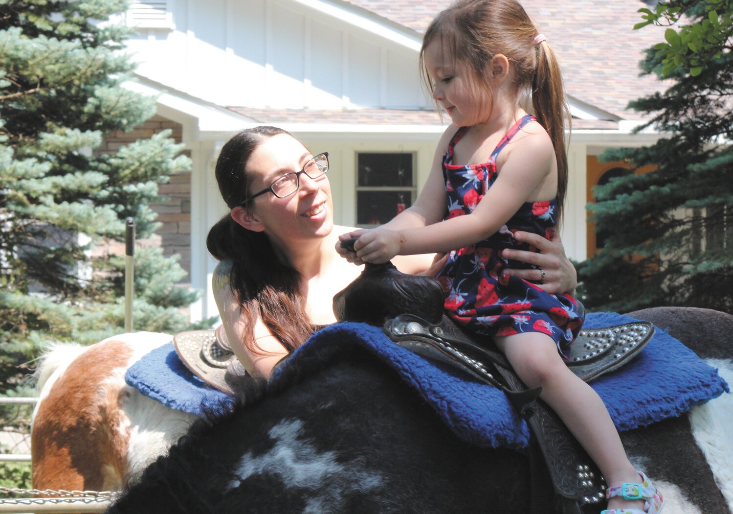 Margot Cline, 3, gets encouragement from her mother while riding a pony Friday in the Children's Area at the Strawberry Festival.
