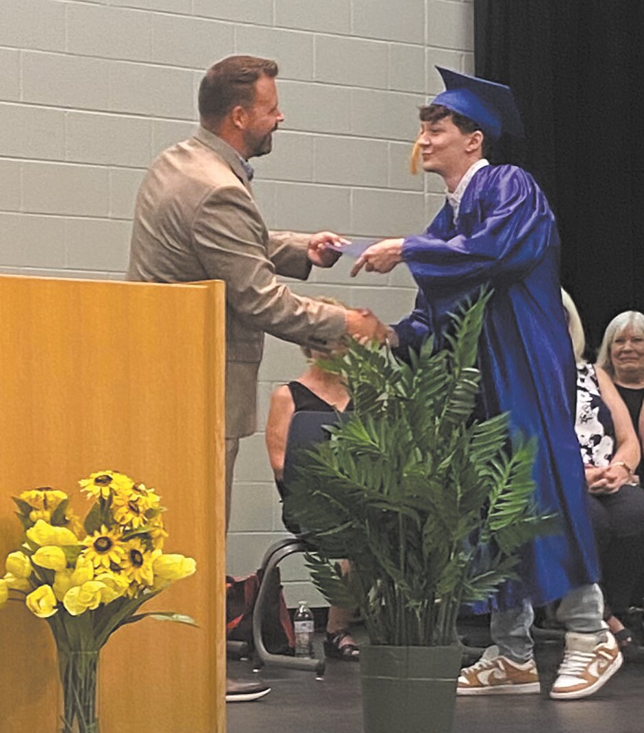 Dr. Rex Ryker hands Graham Spires a diploma.