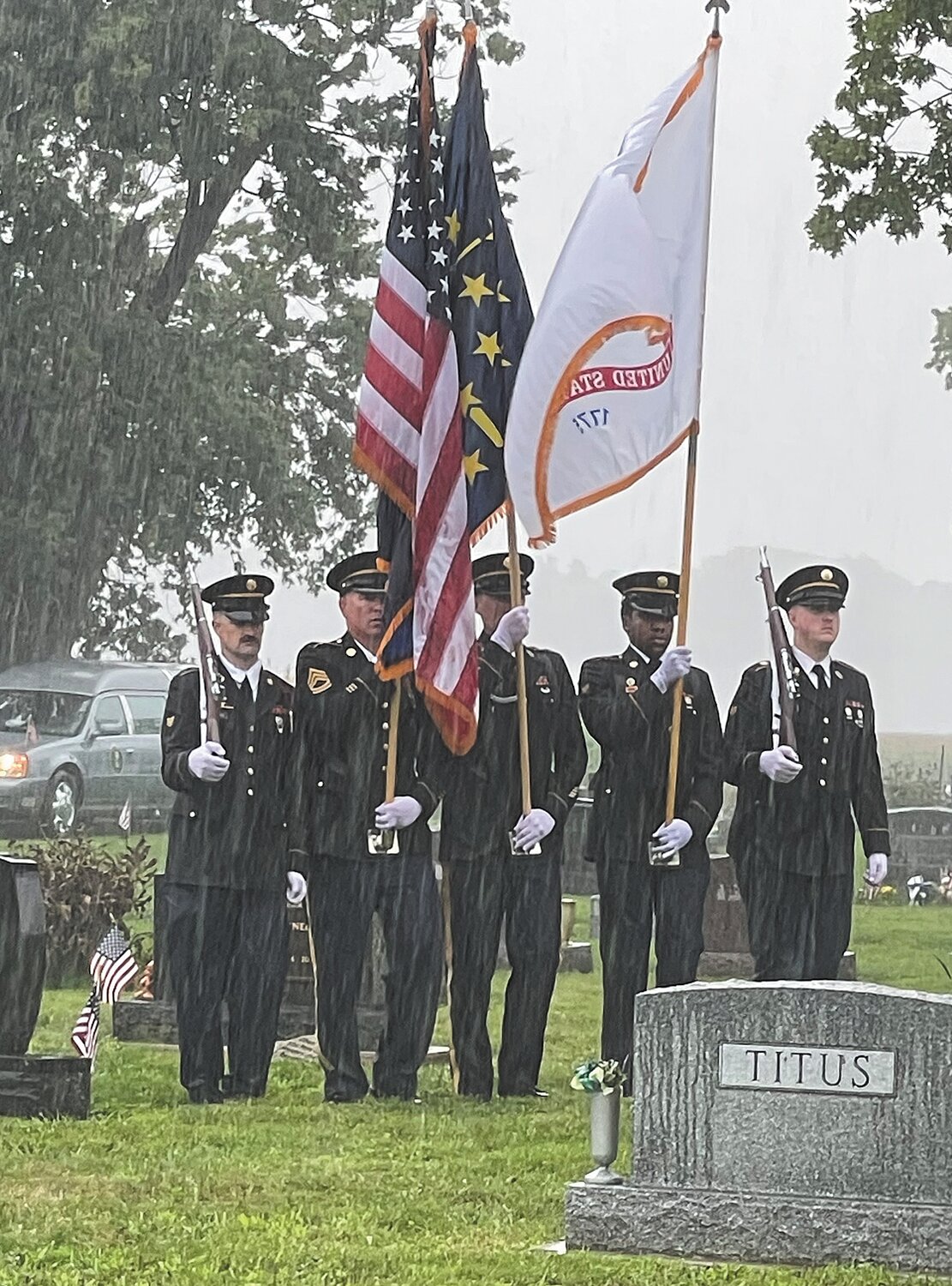 Members of the Indiana National Guard Color Guard stand in the pouring rain.