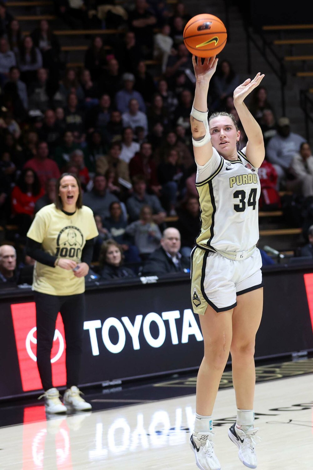 Caitlyn Harper of Purdue - hitting a three-pointer as coach Katie Gearlds reacts in the background
