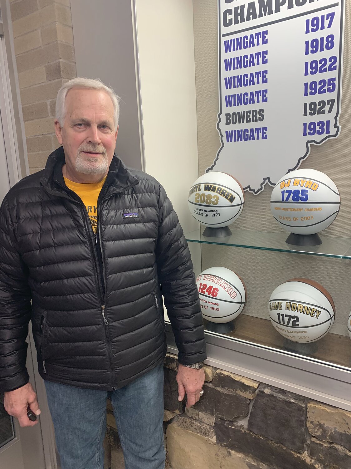 Daryl Warren stands at the North Montgomery trophy case next to the basketball representing his 2,083 points he scored at Linden which is still the most points in Montgomery County history.