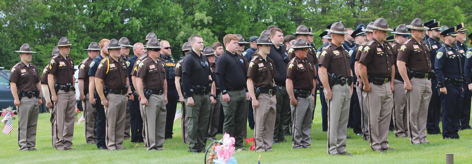 Officers stand at attention near the grave of Lt. Russell Baldwin, a Crawfordsville officer who died in the line of duty 50 years ago this August.