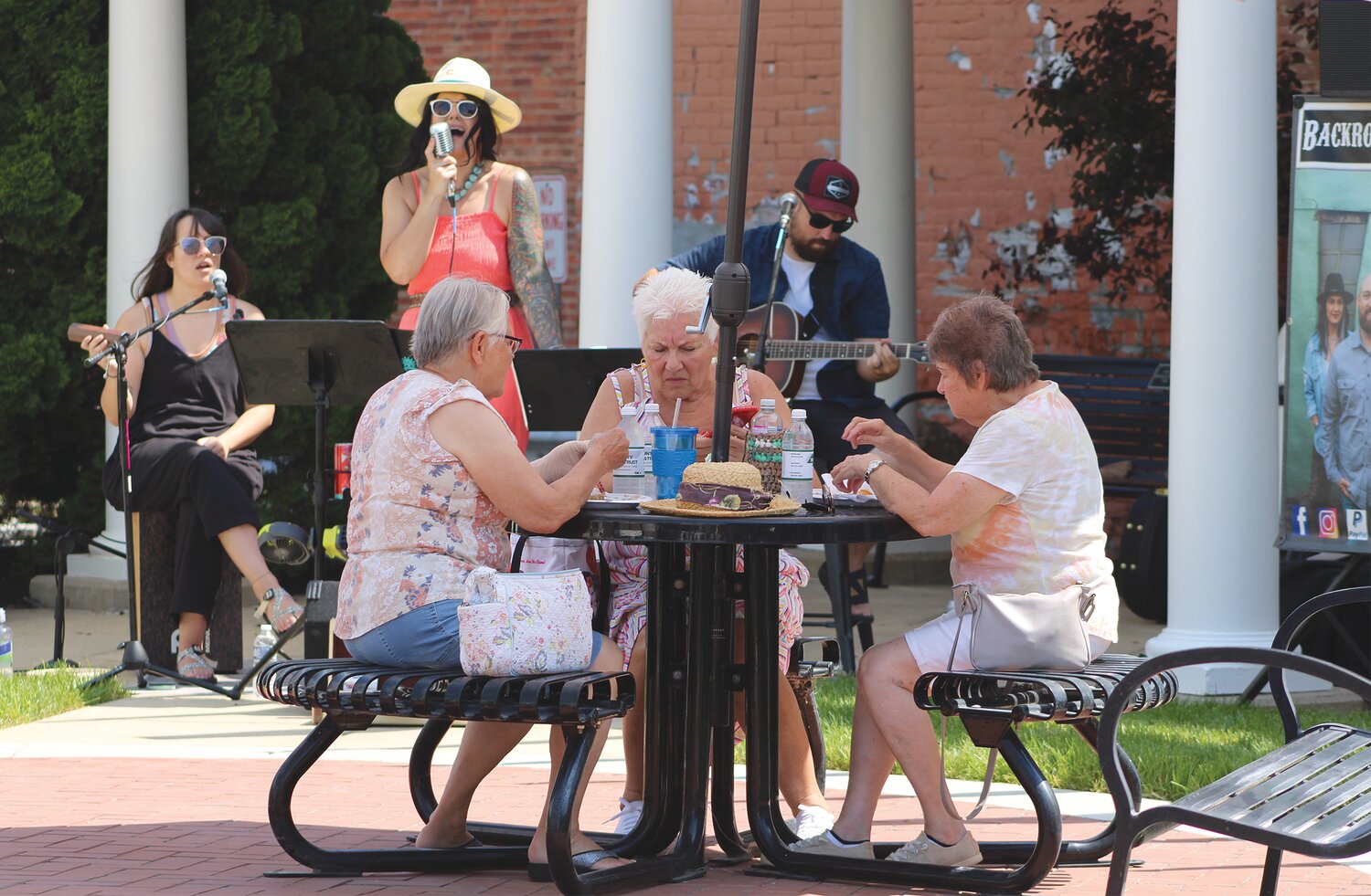 Volunteers serve lunch from China Inn while members of Backroad Revival entertain the crowd Friday at the Marie Canine Plaza. It was the first of three lunch events planned this summer by Crawfordsville Main Street.