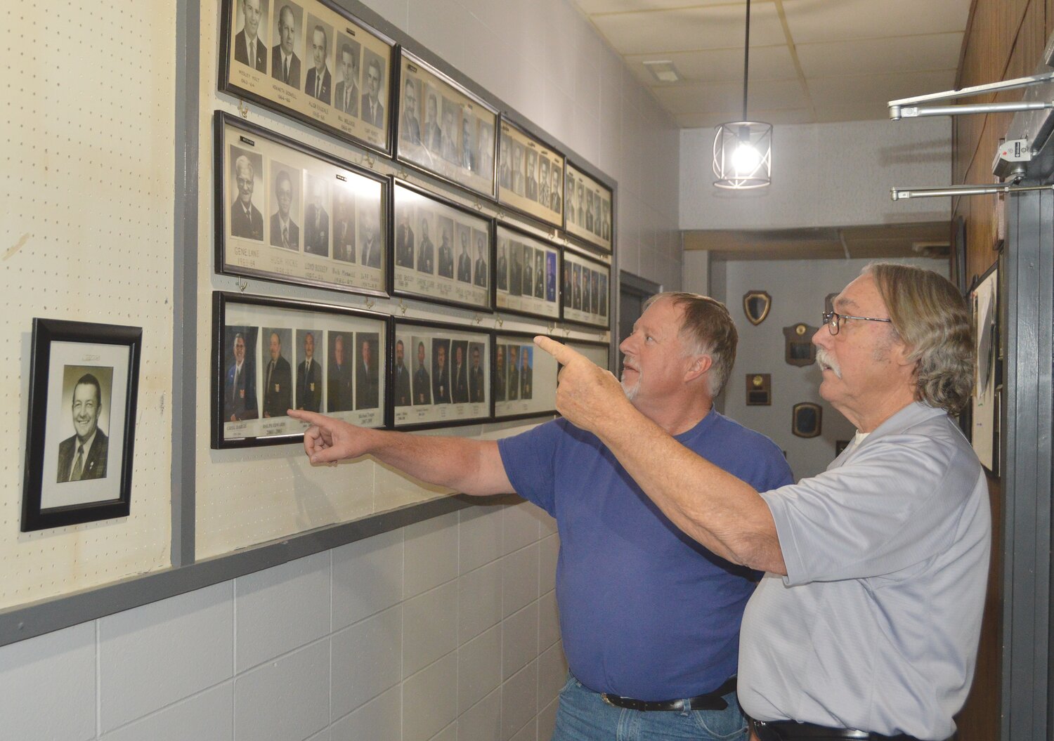 Gary Harrison, Past Worthy President and Past State President, right, and trustee Brett Cating discuss the history of the local Eagles Aerie 1005 by the display of past presidents.