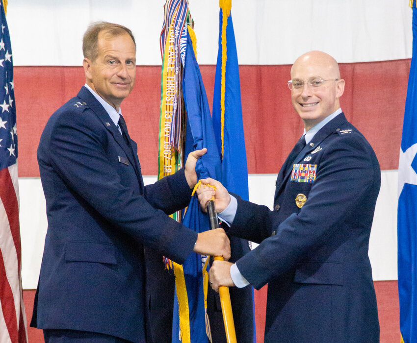 Maj. Gen. Corey J. Martin, left, hands the guidon of the 436th Airlift Wing to Col. William C. McDonald, the newly appointed commander of the Dover Air Force Base, on Friday.