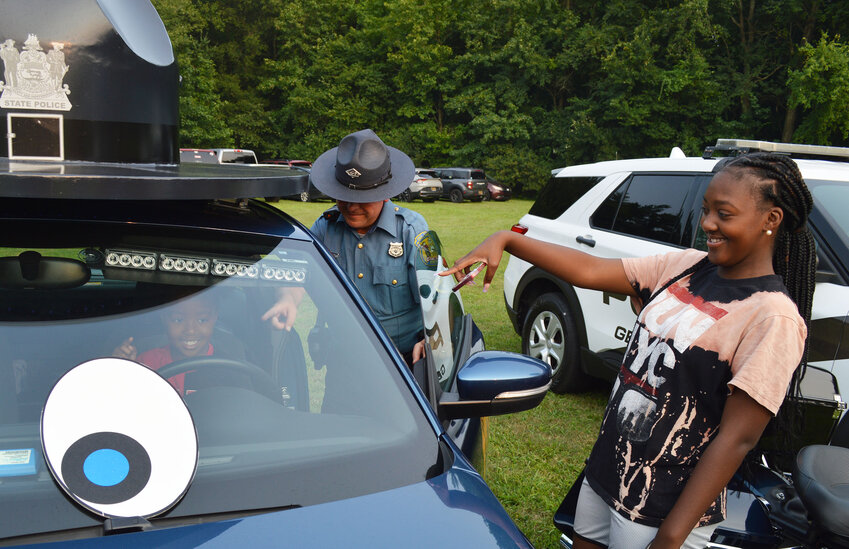 At the wheel of Delaware State Police vehicle Danielle &quot;Dani&quot; Blue is 3-year-old Taliyah Sample, as her mom, Bebe Sample, and Trooper Lewis Briggs III look on at Georgetown's National Night Out on Tuesday.