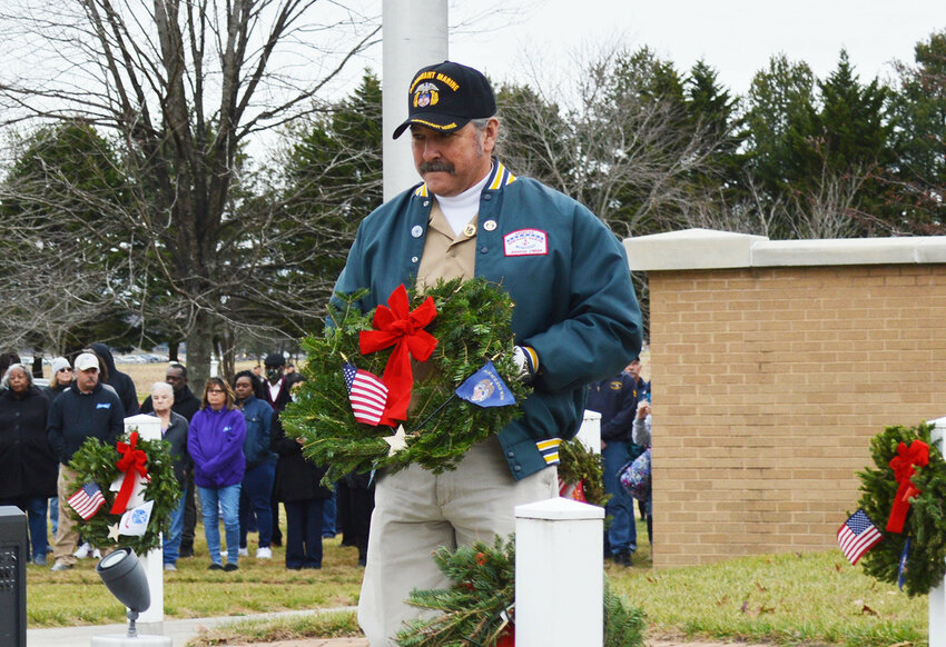 Delaware State News/Glenn Rolfe.Eric Clarke carries the wreath for placement in recognition of the Merchant Marines Saturday during Wreaths Across America Day at the Delaware Veterans Memorial Cemetery in Millsboro.