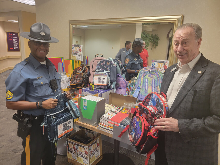 Delaware State Police Master Cpl. Alfonso Jones III, left, of the Community Outreach Unit stands at a table of donated school supplies with Bally's Dover Vice President and General Manager Nick Polcini.