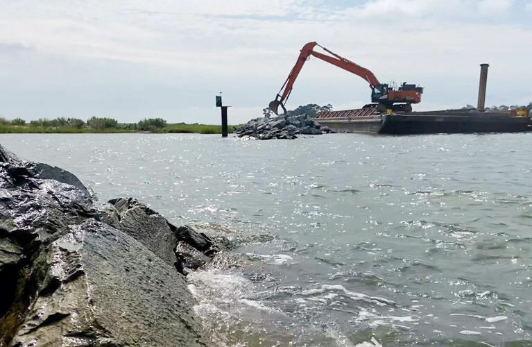 A long-reach excavator places chunks of granite along a stone sill being constructed in August to help restore Barren Island in the Chesapeake Bay.