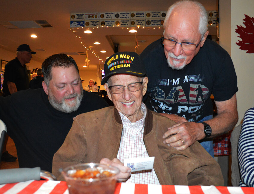 Decorated World War II hero Ernie Marvel smiles as he receives a free American Legion Post 24 membership card from the post's adjutant, George Herrman, right, during a Veterans Day celebration Saturday. Looking on is Mike Oxbrough.
