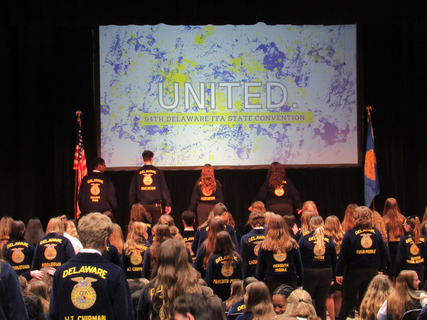 The National FFA Organization members gather at the front of the stage to get the convention's last session started with some line dances.