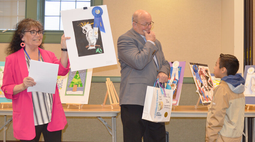 During a prior meeting, Jeanne Locklair, Georgetown Arts &amp; Flowers' vice chair of art, holds up Georgetown Elementary School fourth grader David Zuniga's Student Art Show first-place piece, as Mayor Bill West speaks with him. The show was sponsored by Georgetown Arts &amp; Flowers and held at the Georgetown Public Library, both of which were Georgetown Recreation, Education, Arts Trust Fund recipients in 2023.