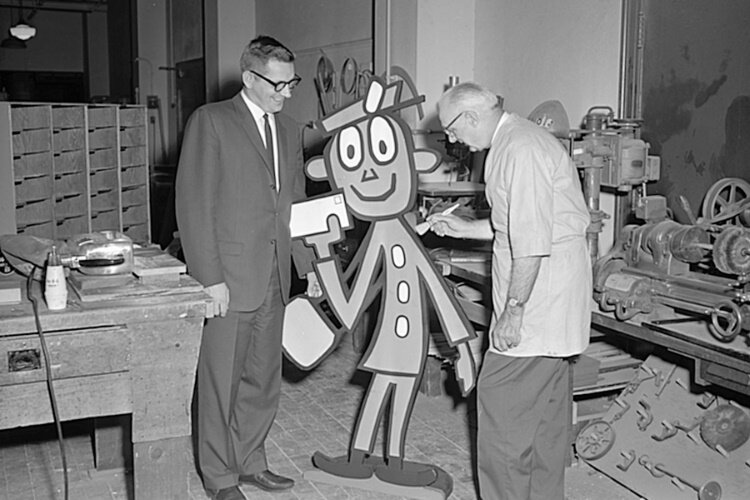 George Keagy, left, a Post Office Department official during the 1960s, watches a worker create a Mr. ZIP standup. The wooden standups were distributed to Post Offices to help promote ZIP Codes.