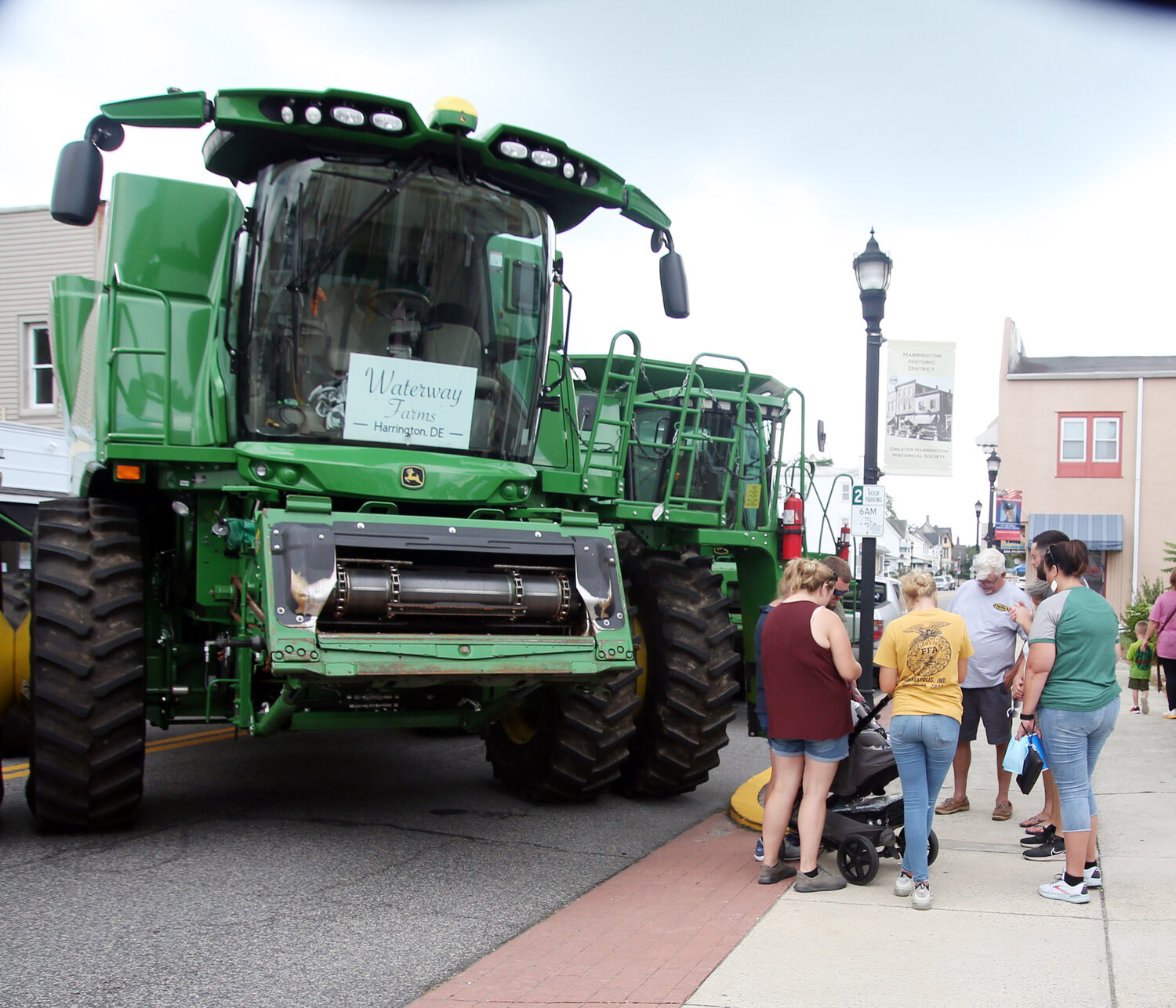 Caleb Dunn, lead pastor of Calvary Wesleyan Church in Harrington, leads a "Blessing of the Combines" Saturday at Harrington Heritage Day. Dale Blessing, Melissa Blessing and Kellie Yeager were there from the Waterway Farm. Harry Raughley of the Taylor and Messick John Deere dealership drove in the second combine.
