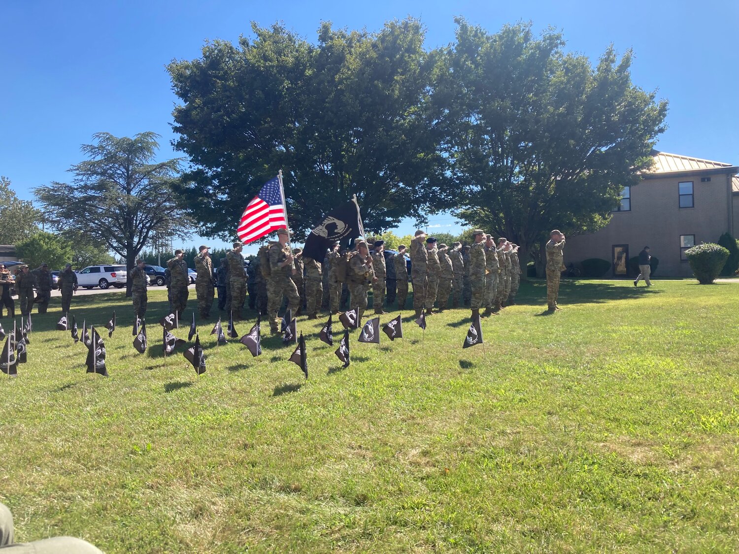 A 50-person formation salutes the United States and POW/MIA flags as they pass by during a ceremony at Dover Air Force Base on Friday afternoon.