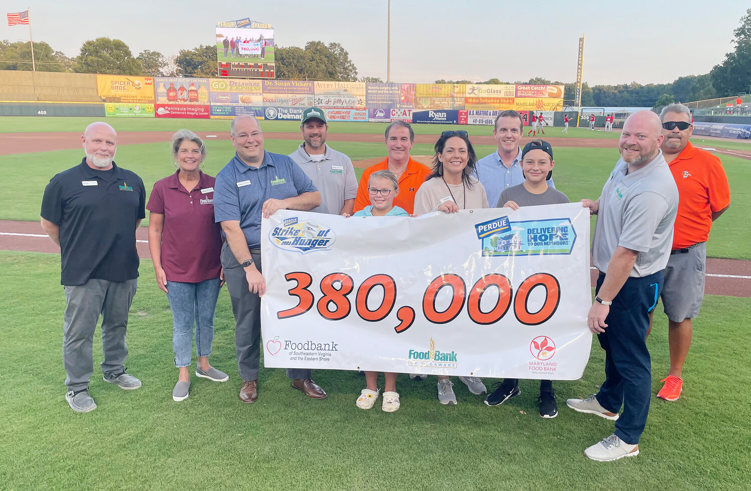 As part of Perdue Farms’ “Delivering Hope to Our Neighbors” initiative focused on improving the quality of life in our communities through hunger relief, the company teamed with the Delmarva Shorebirds and three Delmarva Peninsula food banks to generate 380,000 meals during the season-long 2023 Perdue Strike Out Hunger Challenge on Delmarva. Above from left, John Snarsky of Food Bank of Delaware Milford Branch, Cathy Kanefsky, Chard Robinson and Larry Haas of Food Bank of Delaware, Mike Hooks of Maryland Food Bank in Salisbury, Drew Getty of Perdue Farms, Zach Kellerman of Food Bank of Delaware and Jimmy Sweet of the Delmarva Shorebirds. Directly behind the banner are Melissa Smith of Southeastern Virginia, and her children, Cora and Benji Liskey.