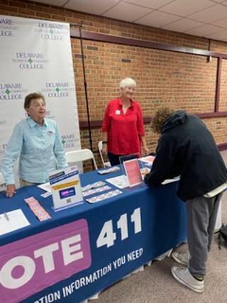 League of Women Voters of Sussex County members Zita Dresner and Carmel Walters assist Delaware Technical Community College students with registering to vote.