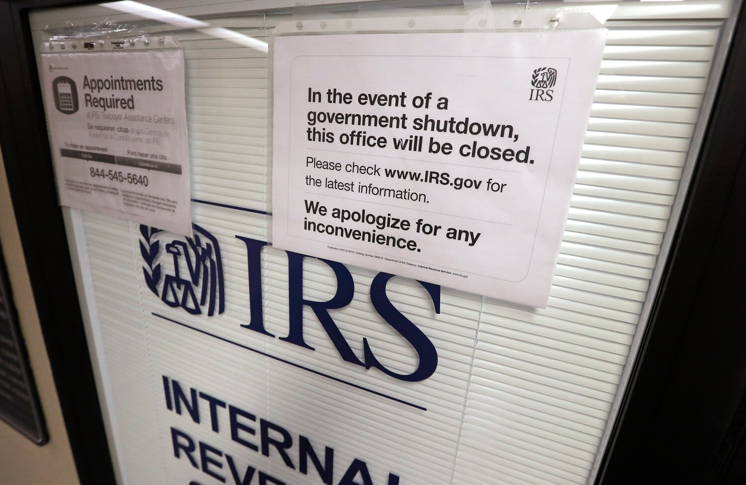 FILE - Doors at the Internal Revenue Service (IRS) in the Henry M. Jackson Federal Building are locked and covered with blinds as a sign posted advises that the office will be closed during the partial government shutdown Jan. 16, 2019, in Seattle. The federal government is heading toward a shutdown at month's end that will disrupt many services, squeeze workers and roil politics. It comes as Republicans in the House, fueled by hard-right demands for deep cuts, force a confrontation over federal spending.  (AP Photo/Elaine Thompson, File)