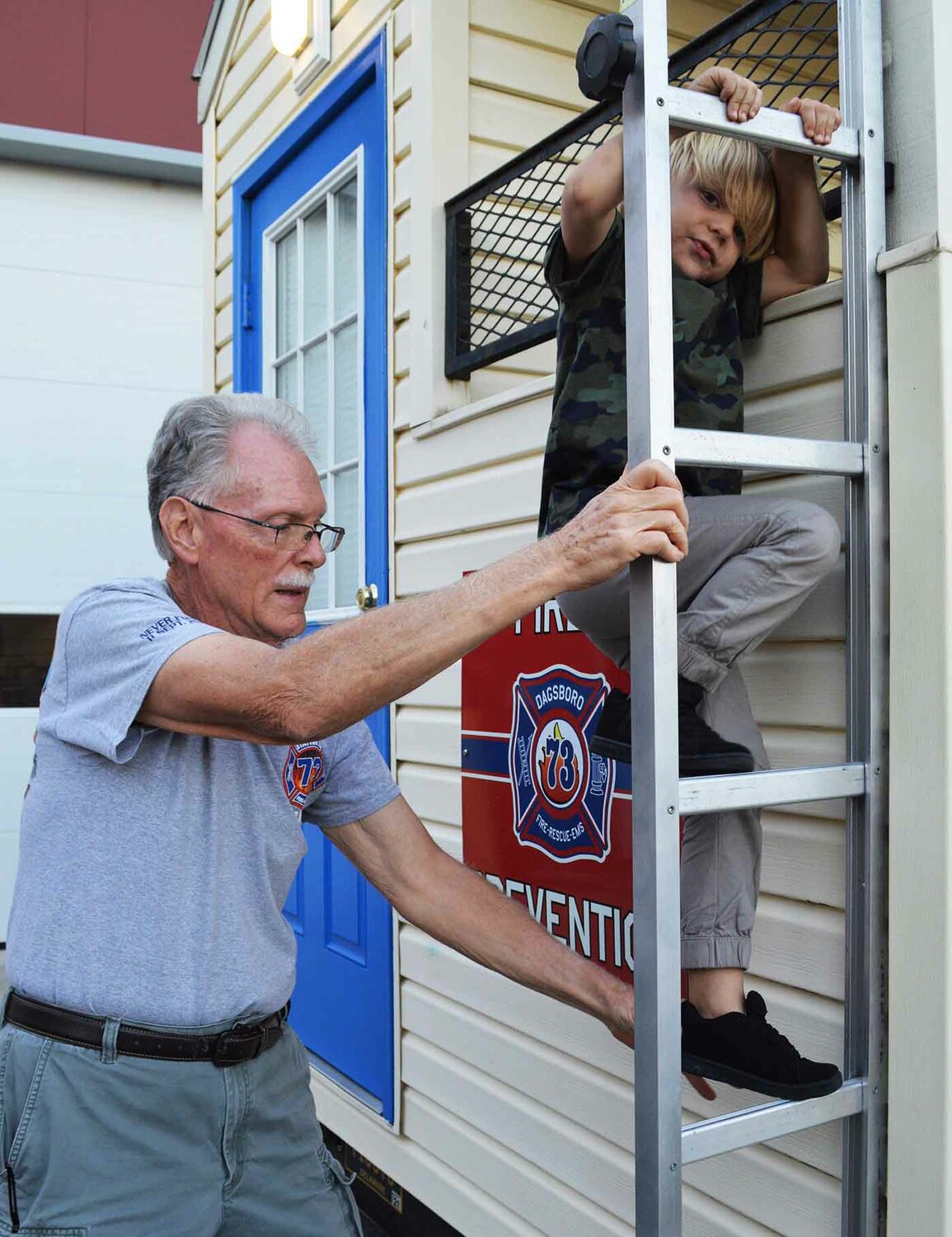Dagsboro Volunteer Fire Department member Tom Glenn helps Kian McCausland climb down the ladder from the department's safety trailer at the 2022 Dagsboro Night Out.