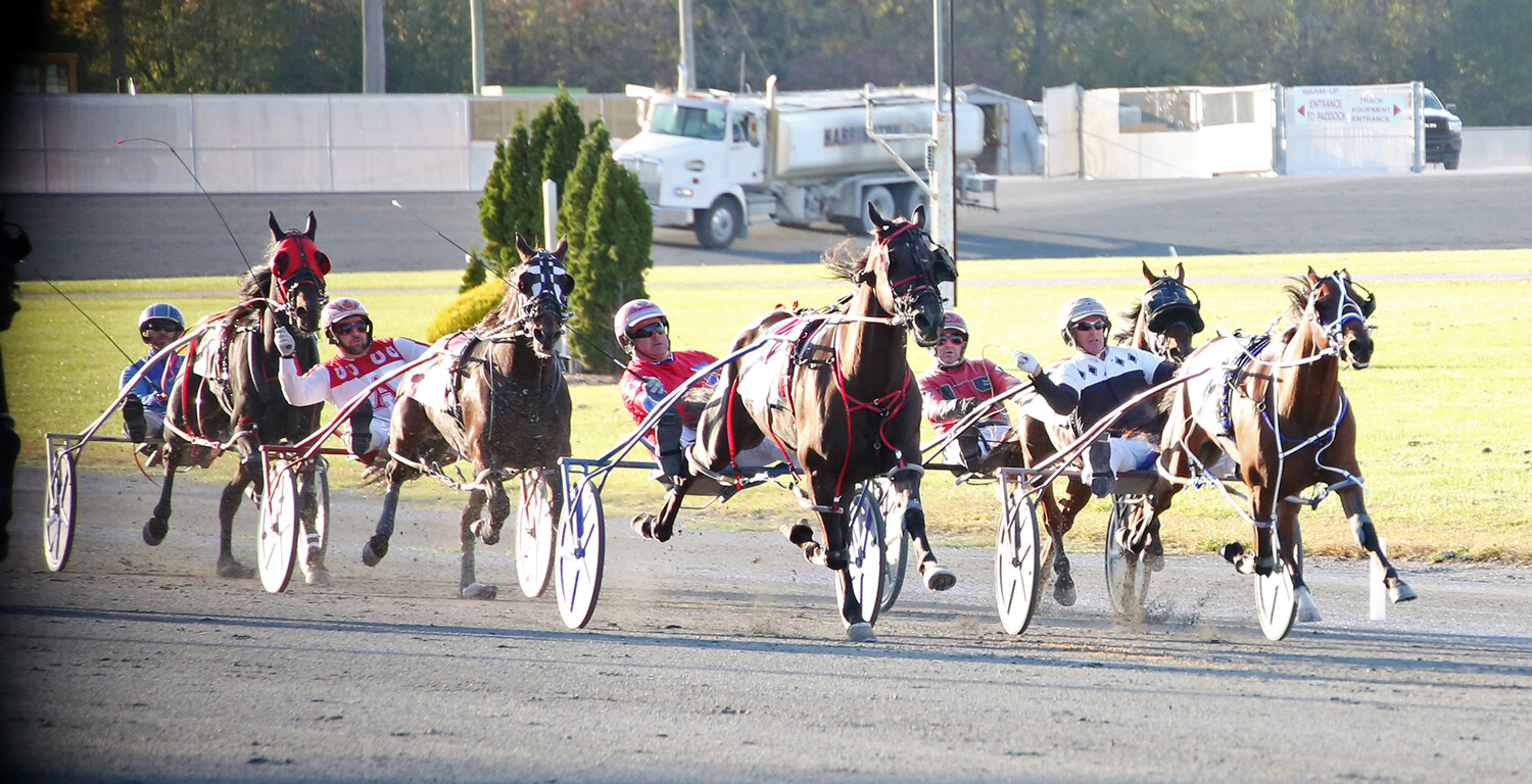 Dude Wheres MyCard, driven by George Dennis, leads the field down the stretch en route to a win in the third race Wednesday night at Harrington Raceway. A $2 win bet paid $77.80.