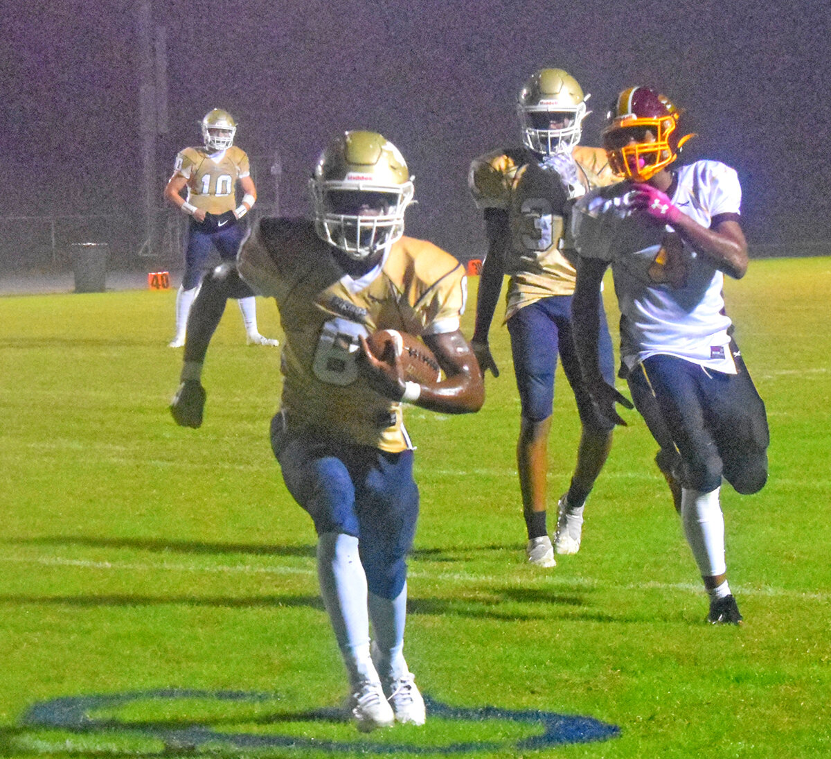 Kayion Marine charged through the rain for a touchdown, laughing as he crossed the goalline. Behind him, at left, is quarterback Blake LaBelle, and #31, Semaj Pinder.