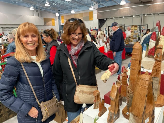 Pattie Buckley, left, and Leslie Brown view hand-carved Santa Clauses during the 2022 Holly Festival.