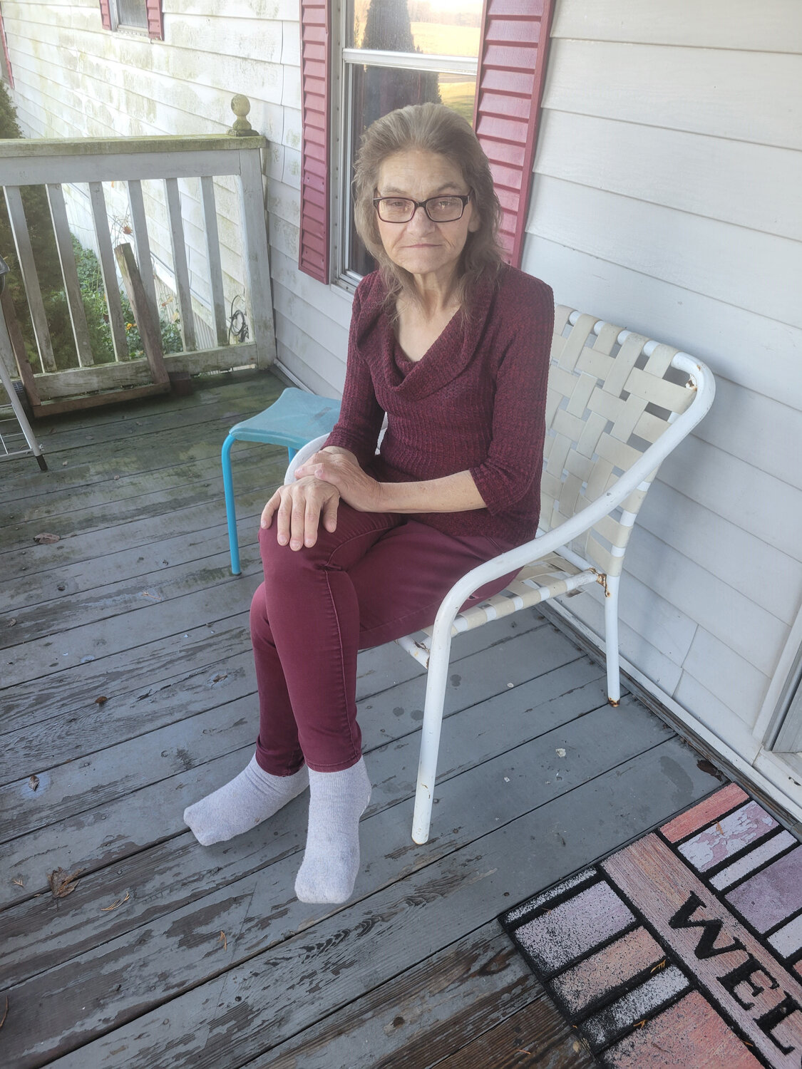 Lorie Bolden sits on the front porch of her home in the Wyoming area. She says she is struggling to pay her bills because of rising grocery and other costs.