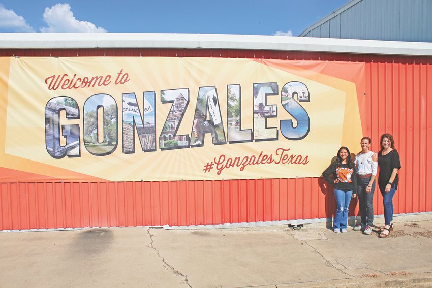 The new banner has been put up on the west wall of the Gonzales Chamber of Commerce, 304 Saint Louis St. It features photos of Gonzales attractions inside the letters of the word &ldquo;Gonzales.&rdquo; Pictured are, from left, Gonzales Chamber and Visitor Center student worker Sianna Ramirez; Chamber executive director Melissa Henderson; and CVB Board member Suzanne Sexton.